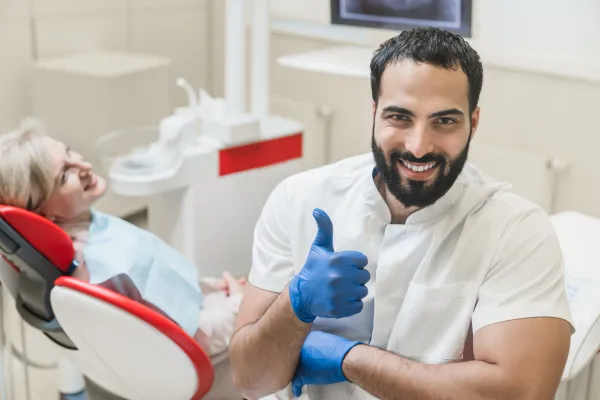 Smiling dentist giving a thumbs-up beside a patient in a modern dental clinic for cosmetic dentistry in Stuart